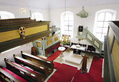 Calvinistische Schlichtheit prgt bis heute den Innenraum der (inzwischen lutherischen) Hugenottenkirche von Wilhelmsdorf. Links an der Empore das Hugenottenkreuz.